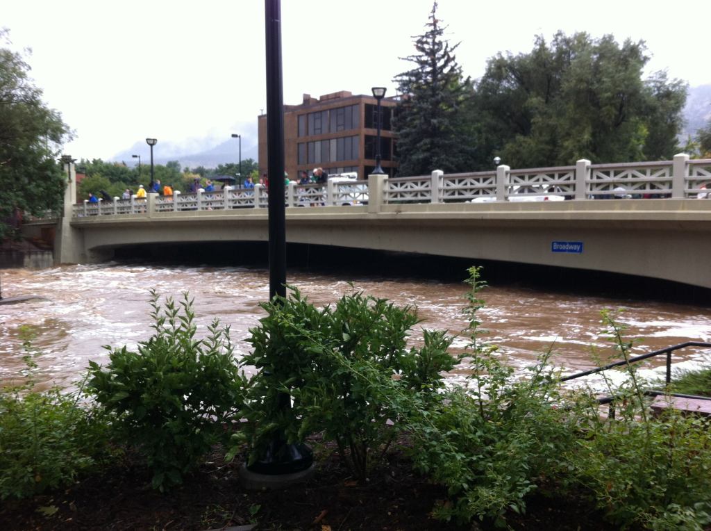 Boulder Creek rising under a bridge in downtown Boulder. Deep beneath the floodwaters are multiple lanes of bike and walking paths and a tall scenic waterfall.