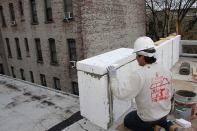 A carpenter from J's Custom Contracting details the foam insulation for a Sto exterior insulated finish system (EIFS) cladding on the parapet wall of a Passive House addition in Brooklyn, New York. The foam will be covered in wire mesh reinforcement and cement, along with additional flashing and roofing details to shed wate.