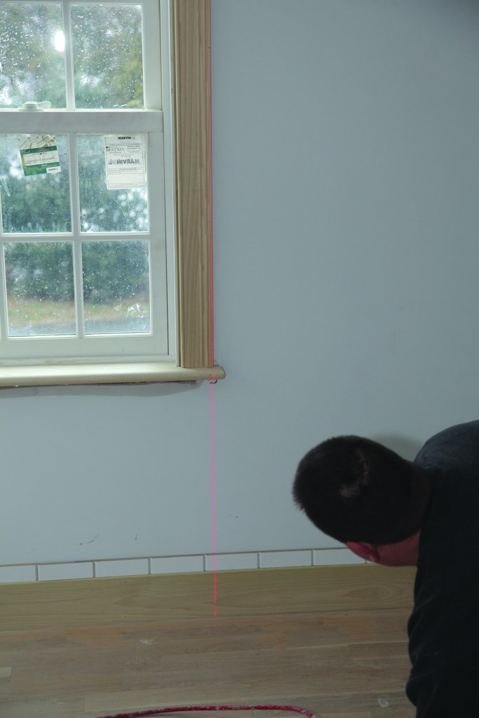 A laser indicated how the edge of the window trim would line up with the grooves on the wainscot.