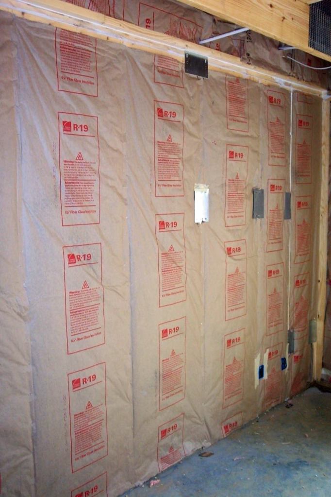 Kraft paper is a better choice than poly for a vapor retarder in a cold climate, because it won't trap summer-time moisture coming from outside an air-conditioned building. The permeability of Kraft paper increases as relative humidity increases. If humidity is high, the permeability of the paper increases and allows the wall to dry out. Photo by Tom Brick.