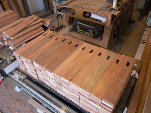 The perforated sine-wave pattern required five basic “forms,” stepping down in sequence and, when flipped end-for-end, stepping up again. The architect’s plans provided a slat length of 12-1/2 inches—not taking into account the 1-inch-wide and 1-1/2-inch-wide respective top and bottom cleats that would secure the slats in the assembly. Finish carpenter Liam McCooe and I ripped 1x4 mahogany decking to a 2 1/2-inch width and then cut it into 15-inch lengths. However, because of the difference in width between top and bottom cleats, we needed to adjust the perforation location for the flipped pieces, by the ½-inch difference, to maintain an equal reveal between cleat and perforation. So, we divided the required count for each slat type into two equal stacks, and devised a simple color code for orienting all pieces.