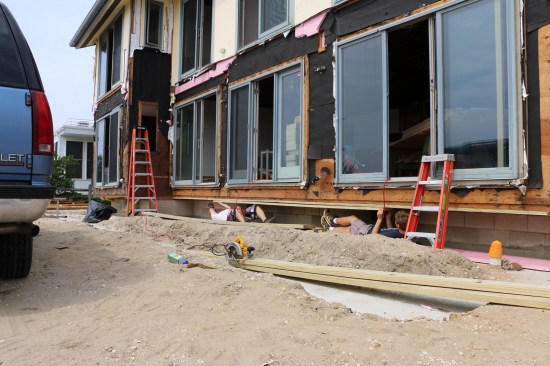 Crew members attach a double sill to the underside of the cantilever. Block will be laid under the sill to support the cantilever and the new porch.