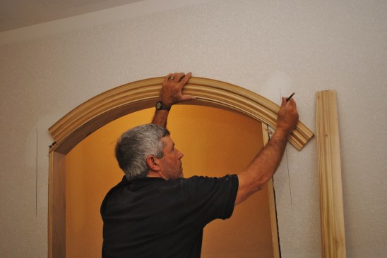 To lay out the miter joint where an eyebrow arch joins the side jambs, first extend the side jamb lines up the wall. Then trace the arch profile extending the lines until they intersect with the side jamb lines.