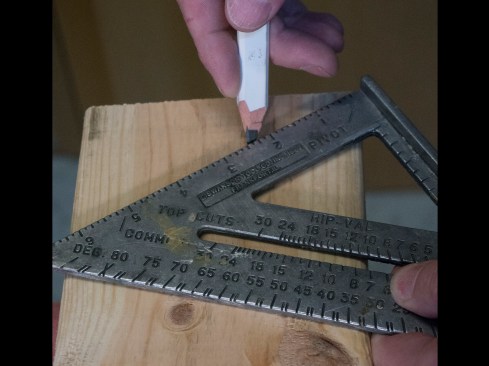 Plumb cut.  I mark a plumb cut on the end of the rafter that will butt the ridge or ledger board. To do this, I line up a my square on the top edge of the rafter and pivot it until the appropriate slope mark (“7” on the square’s “Common” scale for a 7:12 roof) lines up with the board’s edge. Using a sharp pencil, I strike a line, and I use a circular saw with a good blade to cut this plumb line.