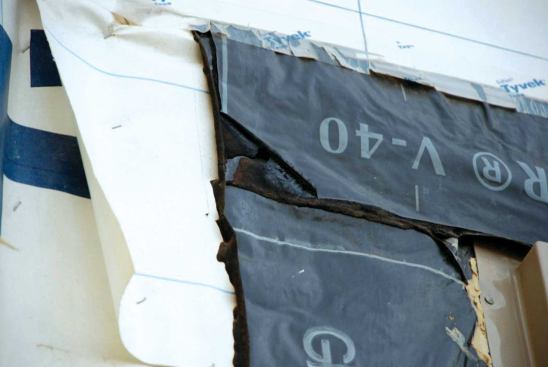 Vapor-permeable tapes keep the weather out, but allow vapor from the interior to pass through. Here the white vapor-permeable tape goes between the window and the opening, which is wrapped in black acrylic tape.