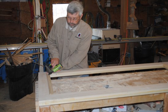After flipping the door and adding molding on the other side of the plywood panel, the author pins molding to one side of the top opening to hold the glass.
