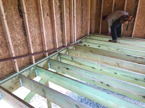 The crew snaps layout lines across the joists for every third row.