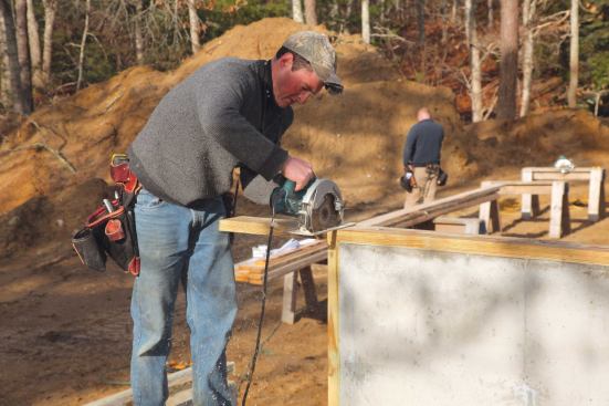 We make sure those sills are plumb before they are anchored. When all the sill stock is attached to the foundation, we saw off any overhanging extra where we'd left the stock long.