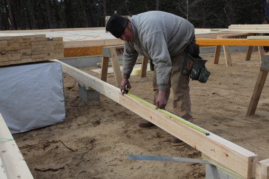 The garage walls are laid out after the house walls. Here a crew member marks out the rough opening for one of the garage door openings.