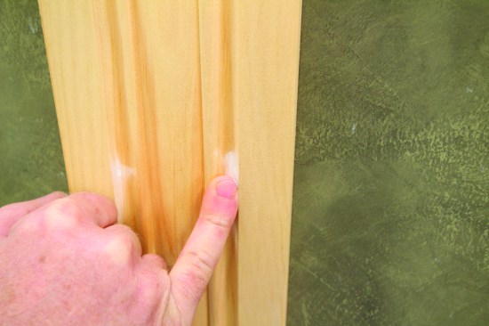 In the grooved areas of the molding, he fills fastener holes with his little finger.