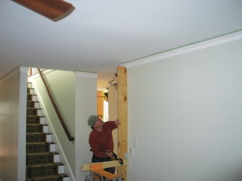 A simple site-assembled rig holds up the far end of the material for me. I clamp a horizontal 2x4 a couple of feet long in a Rockwell Jaw Horse and attach a vertical strip of plywood about 8 inches wide and about 80 inches long. I slide the strip up to the correct height and clamp it to the 2x4 with a one-hand bar clamp.