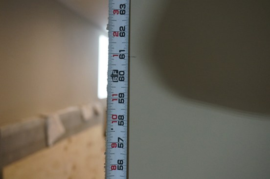 Measure from the floor on the second side. In this installation of doors in a finished basement, the measurement is 60 7/8 inches. The difference between the two measurements must be removed from the bottom of the door jamb to let the door head sit level.