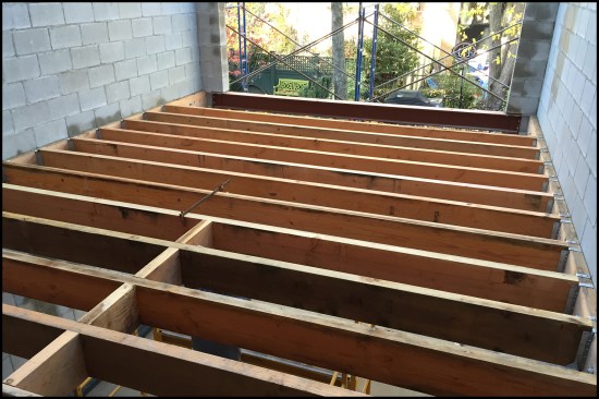 For the addition’s parlor-level (second floor) framing, 3x10 joists were flush-framed to 3x10 ledgers anchored to the block wall’s bond beams. The architect’s initial design called for the 16-inch-on-center floor framing to be left exposed to the garden-level (basement) living room below, but the ceiling ended up being covered with drywall to run and hide wiring and mechanicals.