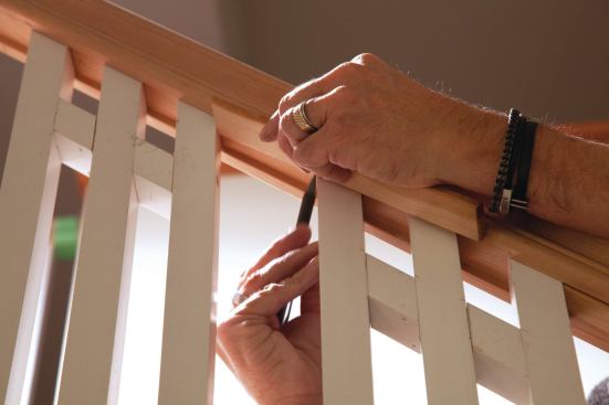 With each three-piece baluster assembly tipped into position and fastened against the rail with brads, the fillet stock that ships with the railing was scribed, cut, and fastened between the end balusters to lock them in place. The final step was to fill any remaining countersinks by gluing in wood plugs, and sanding and painting them. (Also see photo 25.)