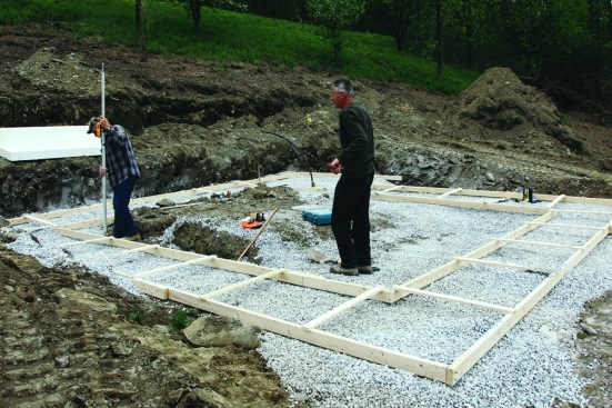 Excavation and footing. The first step is excavating for the foundation assembly. With the excavation open, the crew can put down a layer of crushed stone. The crew sets up 2x4 forms for the footing, using a laser to make sure that they are perfectly level.