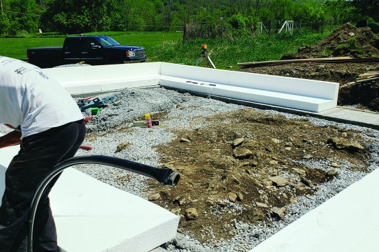 Insulated forms. After the footings set, the crew cuts and fits insulated forms made from EPS foam for the slab. The forms cut easily with a handsaw, and the crew miters the corners.