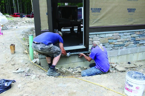 Two crew members carefully lift the stone into place.