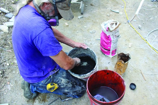 Because the crew works on small areas at a time, they hand-mix the mortar in small batches, adding concentrated masonry tint to the exterior-grade polymermodified thinset to create the black mortar for adhering the stone veneer.