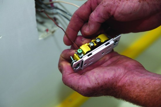 The author attaches the ground conductor first. First he slips the looparound the grounding screw.
