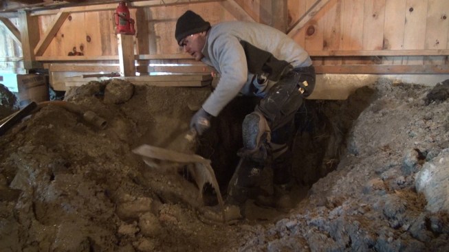 Chris throws out a shovelfull of ice and mud from the excavation. After precast post bases were set, the holes filled up with groundwater overnight.