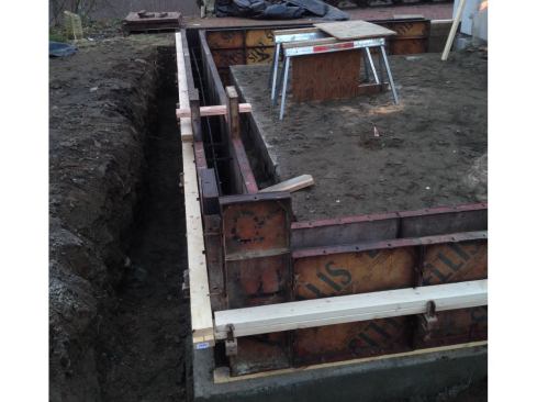 We waited a day, then formed the 8-inch-thick stem walls, which included a 3-inch-wide shelf to catch the edge of the slab. The tops of the walls were set at a height that would allow the new slab to match the finish floor level in the main house as well as maintain proper clearance above grade. We padded out the forms with 2x10s to create the shelf, ran #4 rebar top and bottom, then poured the walls with 3,500-psi to 4,000-psi concrete and wet-set anchor bolts every 4 feet.
