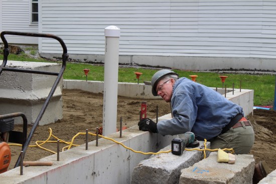 A granite capstone, reclaimed from the existing foundation, lined the remaining foundation perimeter; here, the masonry sub maps outthe rebar locations and angles to accurately line up boring holes.