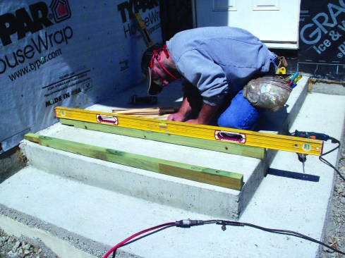 As I set each sleeper in place, I leveled down its length, adding treated shims to fill any voids below the fasteners.