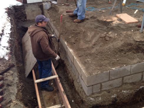 To gain an additional 100 square feet or so for the sunroom, the new frost walls were aligned with the foundation walls of the main building. We left the bottom block courses of the existing frost wall and poured footing in place, using them to hold back the soil on one side of the trench. After excavating to about 4 feet, we formed 10x16-inch (HxW) footings, ran two #4 rebar, and poured 4,000-psi concrete.
