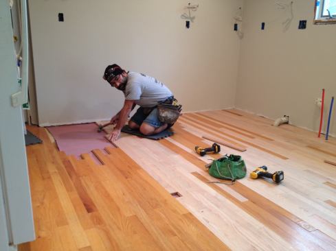 This board is too long to engage. So after ripping the groove, Manny taps it down flat and then taps the end until it snugs against the end of the other board. After the rest of the boards are in, the floor will be sanded and a coat of sealer applied to protect the floor while the kitchen is installed.