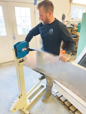 The pans that start the field of the roof start with straight folds in a metal brake. These folds, which will become the "standing seam," are carefully crimped, little by little, to bend the panel to the roof curve.