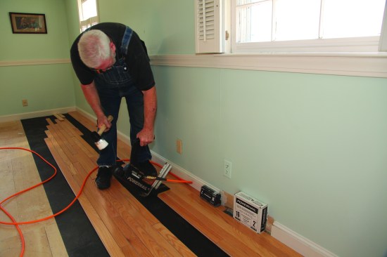 After the first three courses are installed, there is enough room to use a power nailer. This particular nailer has a protective plastic pad that keeps the nailer from scratching the floor finish.