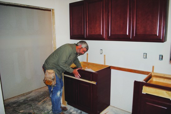 A spacer set on top of doors keeps the drawer faces in line while they’re being attached.