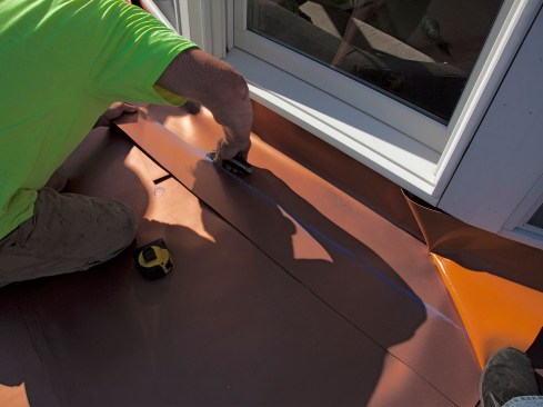 The author’s crew snapped caulklines 6 inches off the wall, then trimmed the flashing strips. A tack-weld can be seen on the lower, right-hand side of the photo.