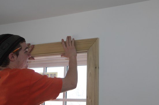 After making a mating 45 degree angle cut on the end of the head casing, the carpenter sets the piece in place with the joint tight to check the fit of the head casing along the head jamb.