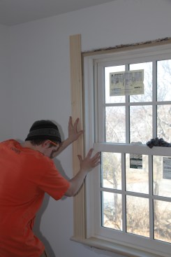 Before cutting the head casing to length, the carpenter squares the end of the second side casing and sets it in place.