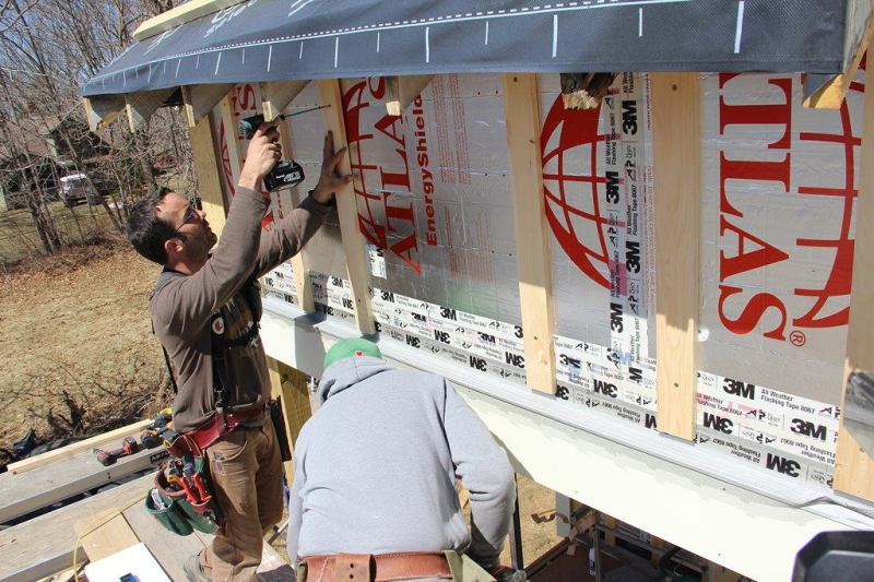 A look at the mostly furred-out wall shows the key durability details of the rain screen system: the foil drainage plane sealed with tape, the furring which creates an air space for drainage and ventilation, and the flashing and bug barrier at the bottom which will allow inflow of air into the cavity, equalizing air pressure across the siding and permitting incidental water to drain out of the assembly.