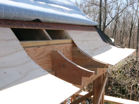 We used a double layer of &frac14;-inch AC plywood to sheathe the flare, running it about 3 inches past the end of the applied eaves so it would catch the crown molding. After laying down a bead of glue, we bent the first piece in place—orienting the grain side to side between the eaves blocks—and fastened it with 8d ring-shank nails.
