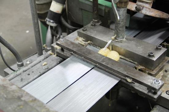 Two strips containing multiple strands of wire are sitting in the machine that glued them together. The machine isn’t running and that blob of glue you see oozed out and cured after the machine was shut down.