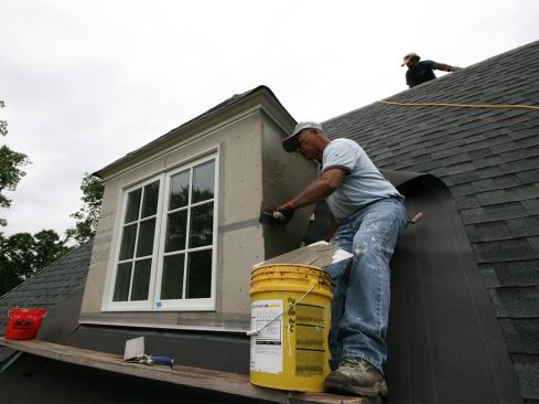 Starting with the dormers, the stucco subs applied a 1/16-inch-thick butter coat of Total Wall T-2000 Base Coat over the Durock…