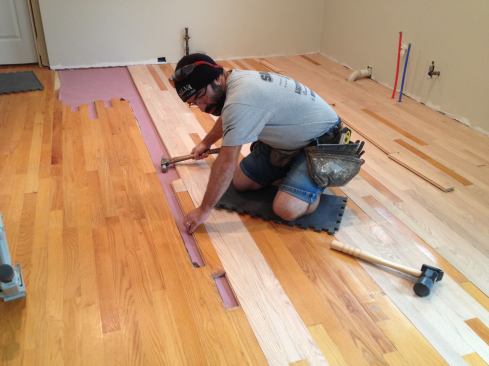 Manny engages the new board and taps it into place as he did with the boards earlier. He uses this method until he runs out of room to start the board and tap on the end of it.