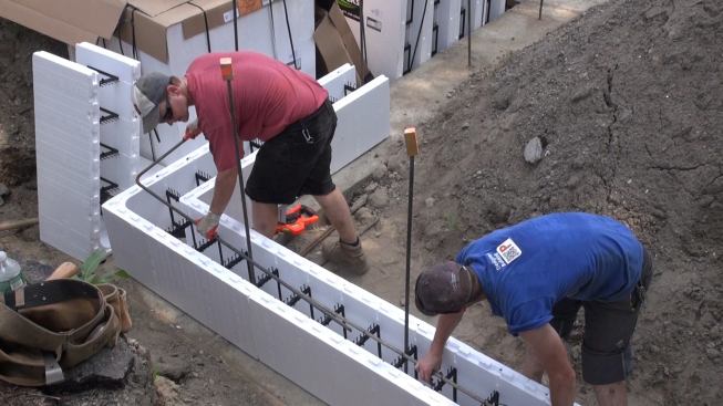 Steve Daly and Greg Hunt set a piece of rebar into the corner of the ICF formwork. The plastic ribs that connect and brace the ICF form blocks are designed to hold the steel reinforcing bars in place, eliminating the labor of tying rebar.