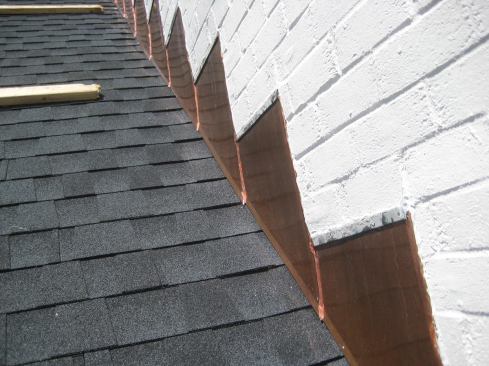 When everything had been cleaned up from laying the new brick, and the brick was painted, copper skirts were slid up under the front edge of each pan and pop-riveted or screwed in place. The copper skirts are further secured with vertical lock seams and serve as a counterflashing to the stepped L-flashings that the roofers wove in with the new roof shingles.