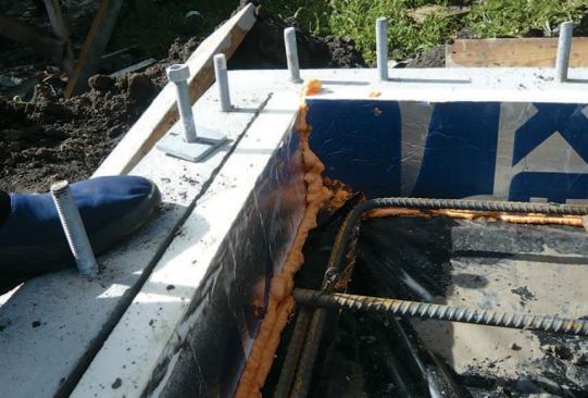 A vertical strip of polyiso board around the inside of the stem wall minimizes heat loss at the slab edge.