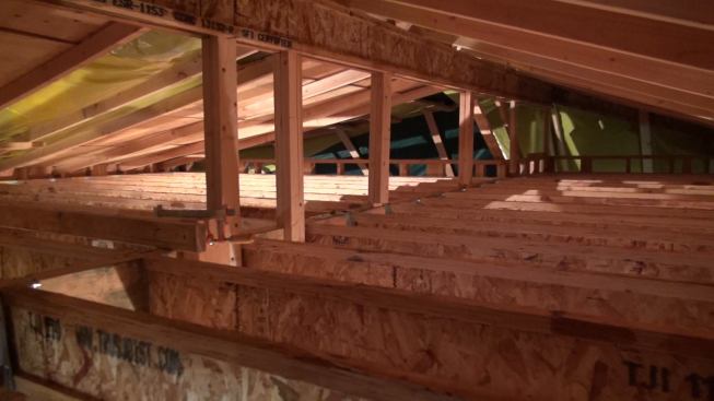 Shown here is the wood I-joist ceiling of the new second floor, with a temporary pitched roof structure installed above it to hold the tarps that Gregor and his crew had to install on an emergency basis as a Pacific storm approached. The temporary 2x rafters and wood I-joist ridge at the top were removed when dry weather returned. The horizontal wood I-joists at the bottom of the frame remained as ceiling and roof structure. The ceiling I-joists were packed up with 2x10s ripped on a taper from 10 to about 3 inches (shown in the coming images), to create a low-slope roof deck which Gregor topped with a waterproof membrane.