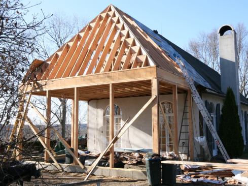 We framed the roof using Douglas fir 2x10 rafters, which were doubled up at the hips. We cut the seats so the top of the rafters ran flush into the rim joists; we would add the overhangs later to match the flare of the existing roof. The steep pitches—13:12 at the main roof and 20:12 on the end—required rafter bevel cuts well beyond the 50 degrees our saws would cut. Instead, we cut the inverse bevel on one end of a block that ran between the king common rafter and the hip, then cut the longest jack square to butt up against it. We repeated this with each jack, running a block from the longer adjacent jack to the hip, square-cutting the next jack and installing it against the block. It required a little more material, but saved a lot of time.