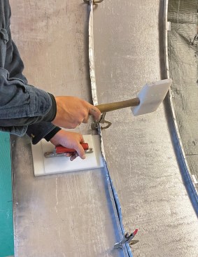 The roofer's anvil and mallet are used again, this time to fold the long leg on the second panel over the bent rib on the first panel.