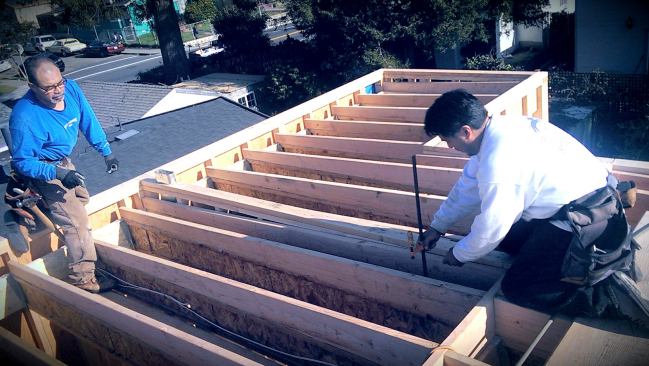 Carpenters framing the sloped build-up that creates the pitch for the new low-slope roof.