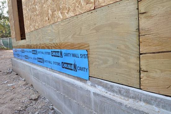 The CCW 705 runs over the concrete slab by 1-2" to air seal and move water away from the sheathing. Notice the dark primer before adhering the peel & stick CCW 705.