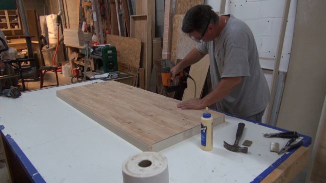 Stapling the plywood back to the panel frame.