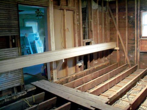 Keeping your balance as you walk on the edges of joists can be tricky and dangerous, so I tacked down a few of the old boards for safe footing. Because storage space in the house was at a premium, I built temporary supports out of scrap 2x4s and loaded all the LVL joist stock into the room.